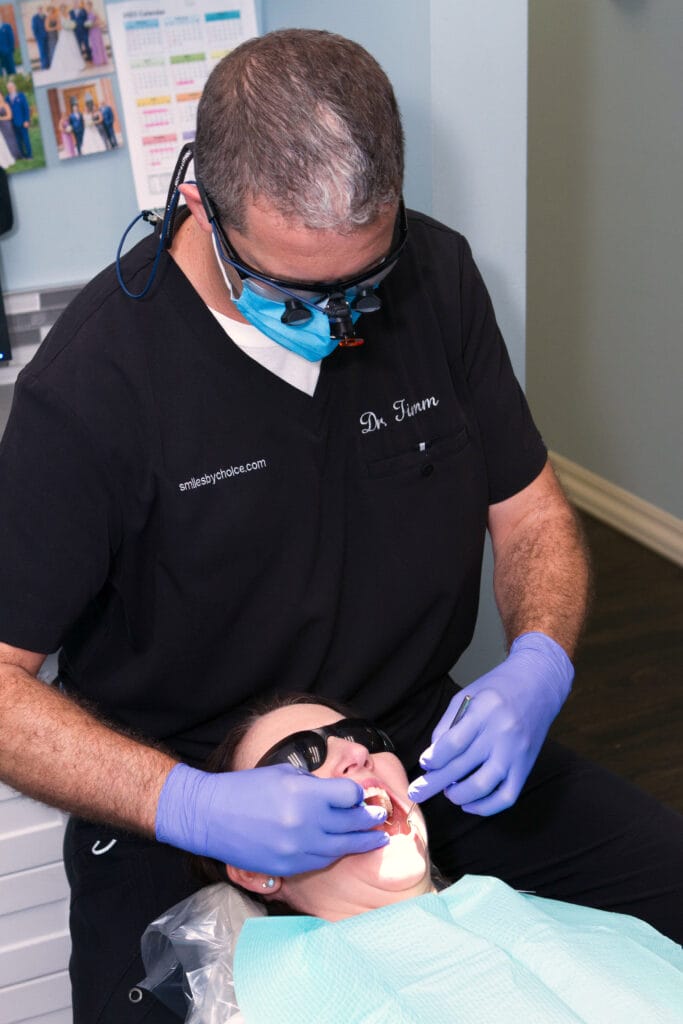 Dentist wearing magnifying loupes and gloves performing a dental procedure on a patient in a treatment chair